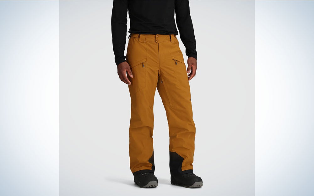 A person wearing an orange pair of Outdoor Research Men's Snowcrew pants