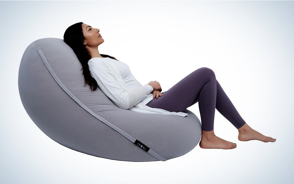 Woman reclining in a grey Moonpod bean bag zero gravity chair on a white background